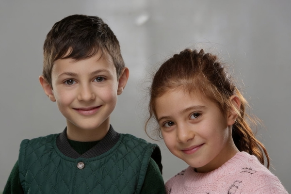 Studio portrait of a boy and a girl, heads together — watermark removed by GoStudio Advanced