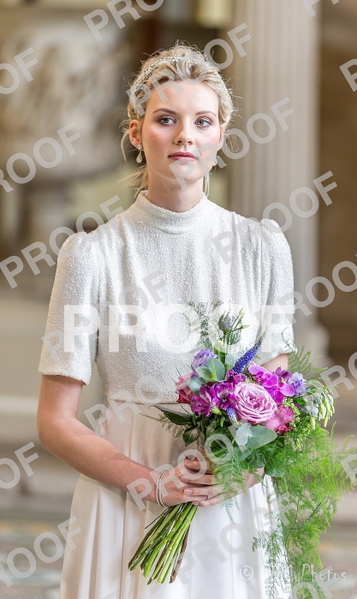 Bride in a white high-necked dress holding a bouquet of roses and lavender