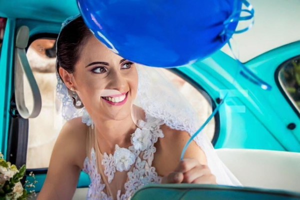 Smiling bride in a lace veil in a turquoise vintage car, blue balloons above — watermark removed by GoStudio Lite