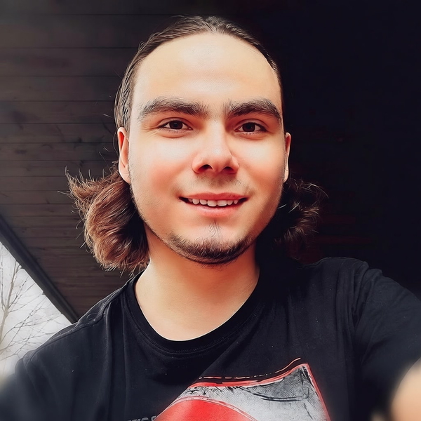Young man with long hair smiling, in a black T-shirt — watermark removed by GoStudio Pro