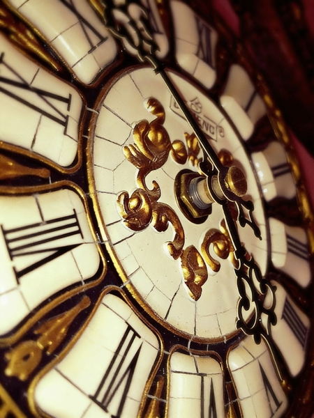 Close-up of an ornate clock face with Roman numerals and gold scrollwork — watermark removed by GoStudio Advanced