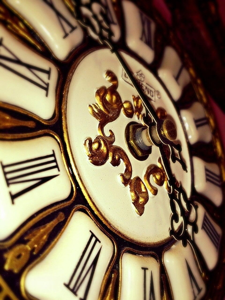 Close-up of an ornate clock face with Roman numerals and gold scrollwork — watermark removed by GoStudio Lite