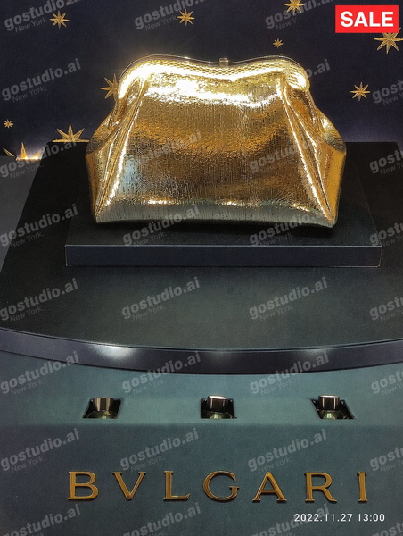 Gold clutch bag on a display plinth above a jeweller’s name