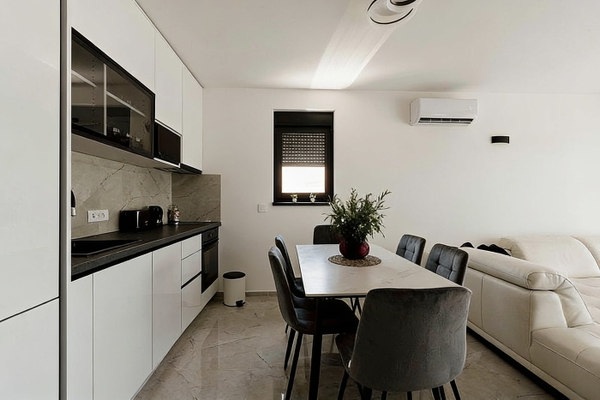 Open-plan kitchen and dining area with white cabinets and grey chairs — watermark removed by GoStudio Advanced