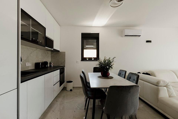 Open-plan kitchen and dining area with white cabinets and grey chairs — watermark removed by GoStudio Lite