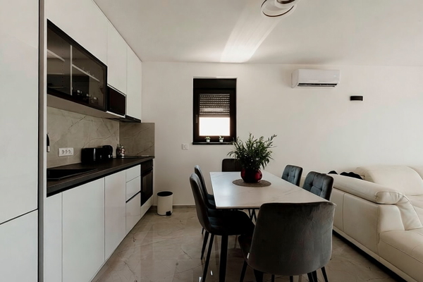 Open-plan kitchen and dining area with white cabinets and grey chairs — watermark removed by GoStudio Pro