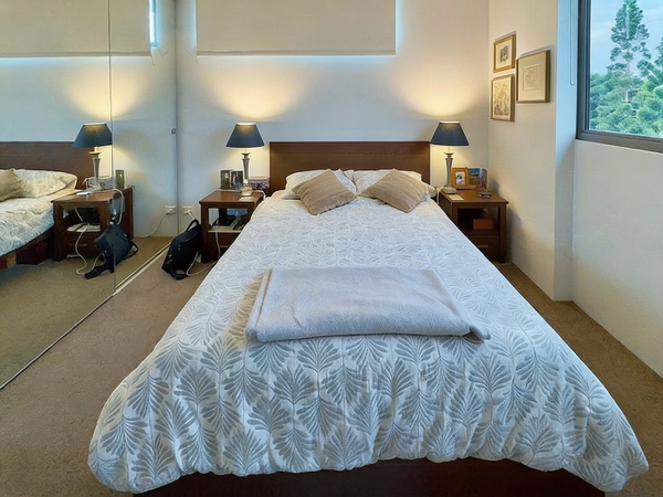 Bedroom with a patterned white bedspread and bedside lamps — watermark removed by GoStudio Advanced