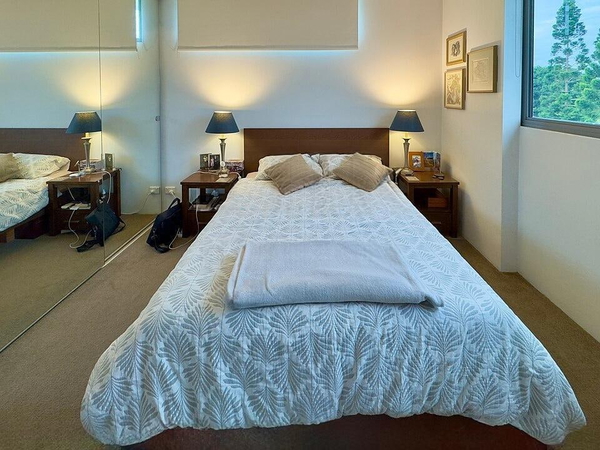 Bedroom with a patterned white bedspread and bedside lamps — watermark removed by GoStudio Lite