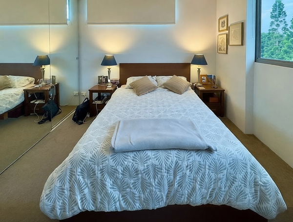Bedroom with a patterned white bedspread and bedside lamps — watermark removed by GoStudio Pro