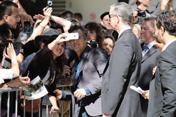 Crowd of fans with phones around a man in a grey suit at a public event — watermark removed by GoStudio Advanced