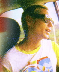 Man wearing a white t-shirt and sunglasses, sitting in the back seat of a car — sample image to denoise