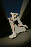 Man in a white hoodie and black shorts running on a skateboard — sample image to enlarge