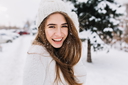 A smiling woman in a white sweater and hat standing in the snow — headshot before AI full-body generation.