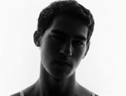 A young man in a tank top looking at the camera on a white background — a sample portrait for the AI age changer.
