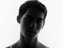 A young man in a tank top looking at the camera on a white background — a sample portrait for the AI age changer.
