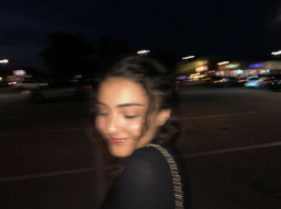 A woman in a black dress on a city street at night — a sample portrait to try in the AI age progression tool.