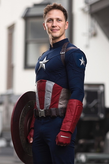 A man stands smiling, holding a circular shield. The background is blurred, suggesting motion. A man stands smiling, holding a circular shield. The background is blurred, suggesting motion.