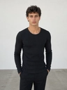 A man in a plain black long-sleeve top against a white wall, before the AI clothes changer swaps the outfit