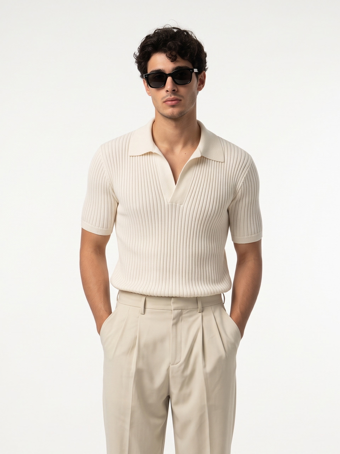 A man in a cream ribbed polo standing square to a plain white studio wall with his back straight and his shoulders level. A man in a cream ribbed polo standing square to a plain white studio wall with his back straight and his shoulders level.