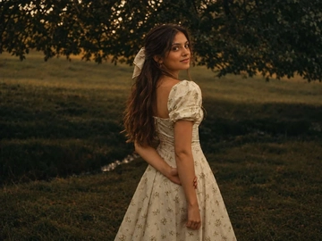 Woman in a floral dress in a field, face lost in deep shadow — before skin tone correction Woman in a floral dress in a field, face lost in deep shadow — before skin tone correction