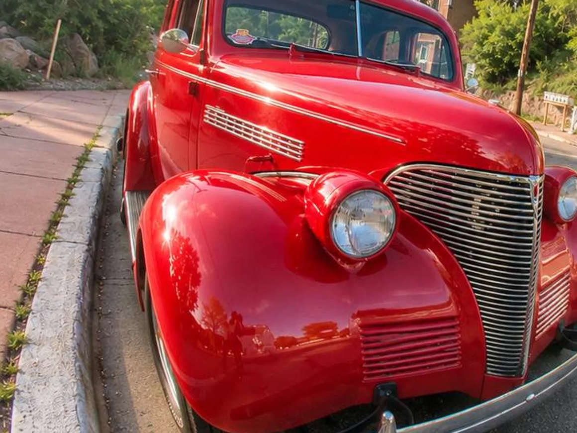Fisheye photo of a red vintage car on a street, the curb and poles curving around it, before fisheye correction Fisheye photo of a red vintage car on a street, the curb and poles curving around it, before fisheye correction