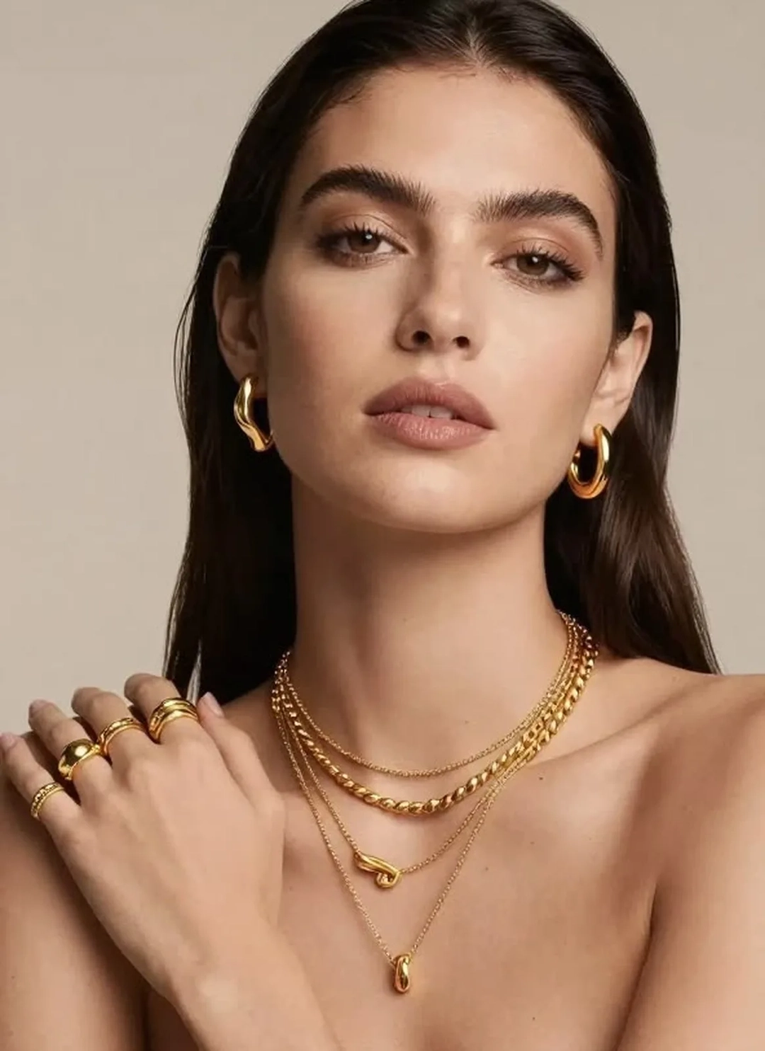 Woman with hoop earrings and three gold chains, before removing the jewelry