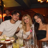 Sample photo of three friends at a bar with a man standing behind them, to try the AI people remover